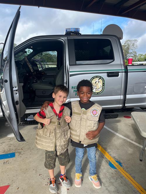 Two boys posing in Fish and Wildlife vests.